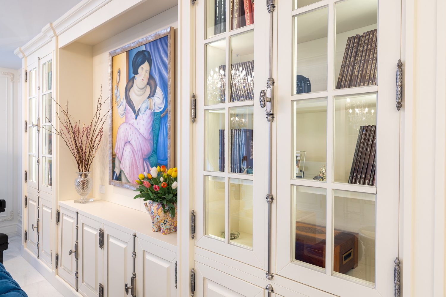 Detail of commissioned cabinetry with glazed doors, silvered hardware and integrated shelf lighting