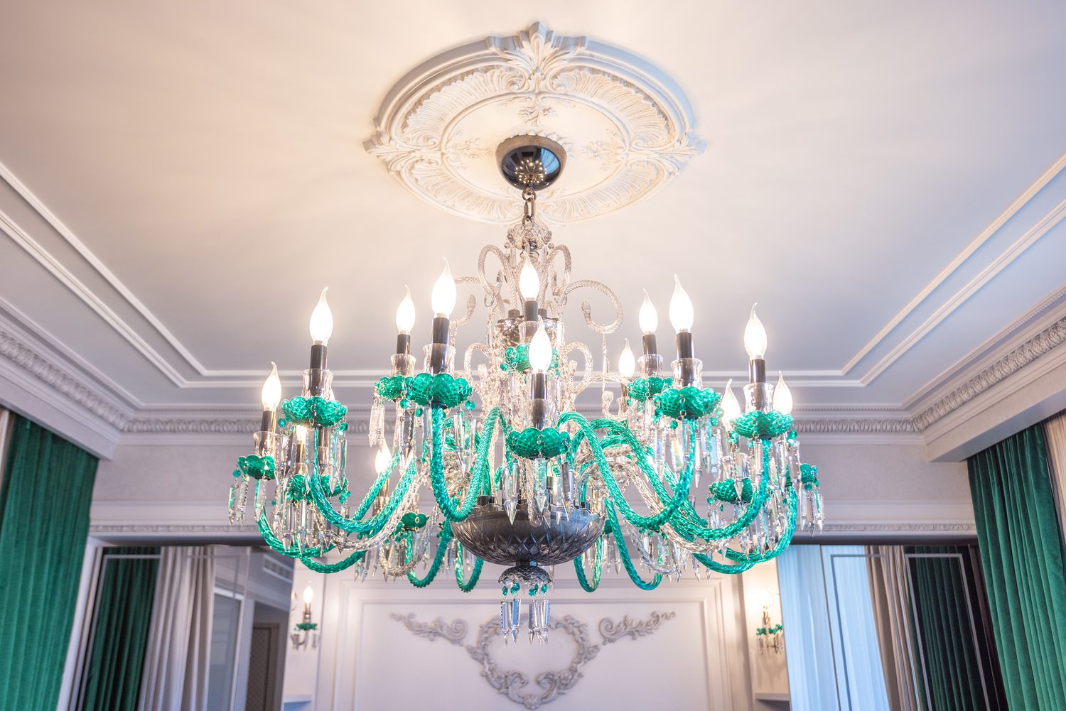 Emerald Murano glass chandelier below a carved plaster ceiling rose in the primary bedroom