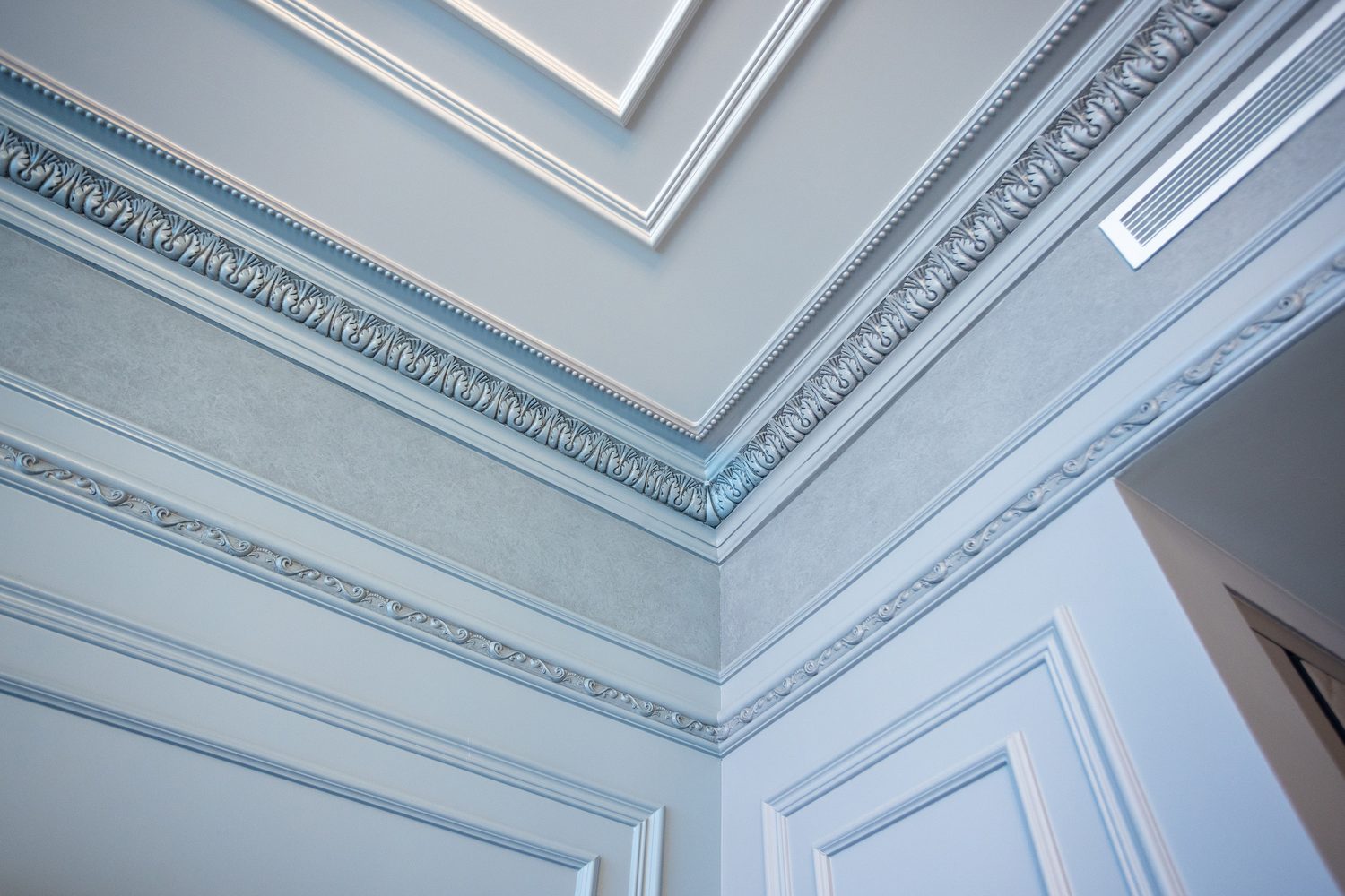 Detail of layered ornamental cornice and ceiling mouldings in pale grey and cream