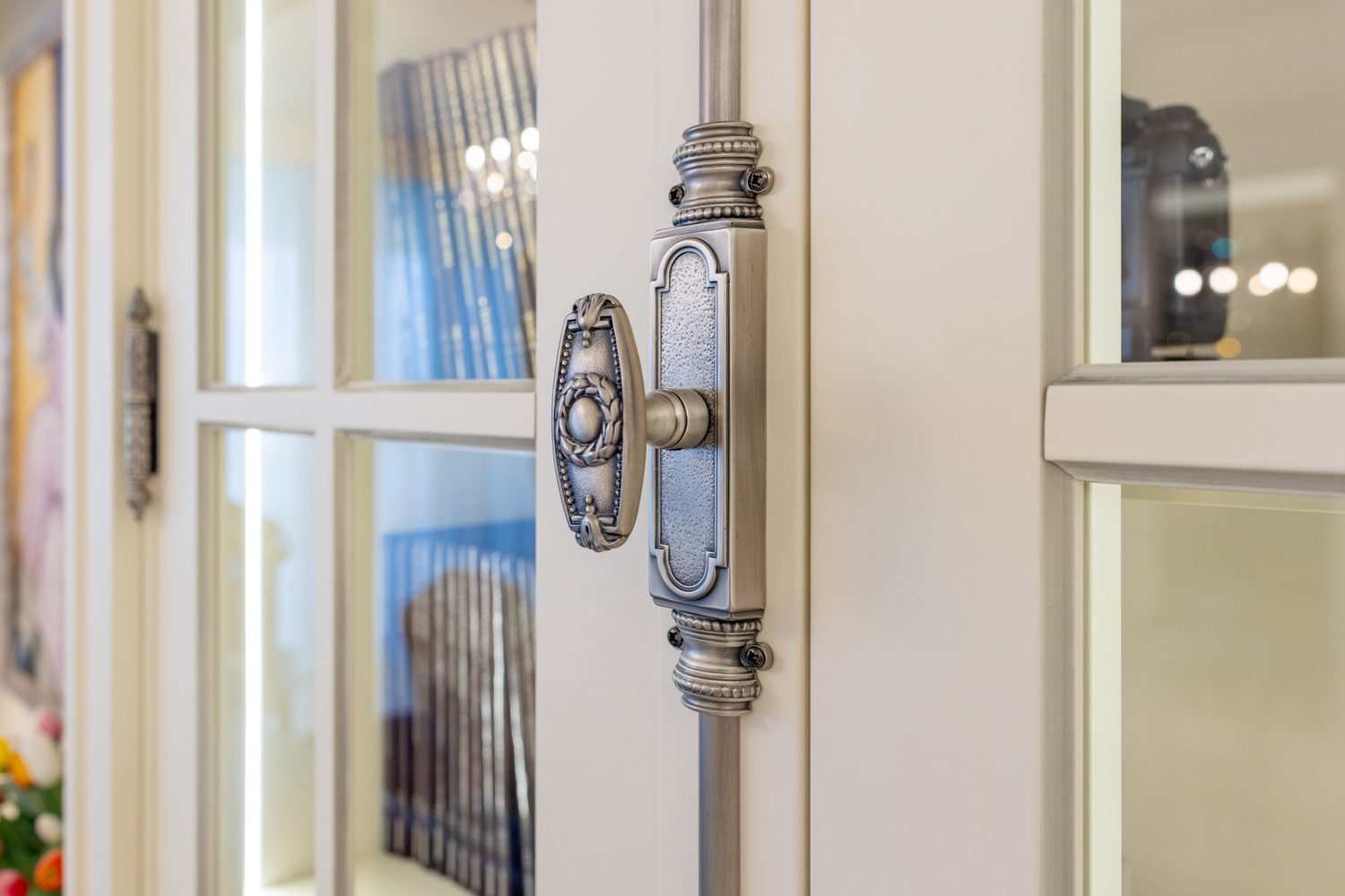 Detail of an ornate silver door knob and backplate on a panelled door