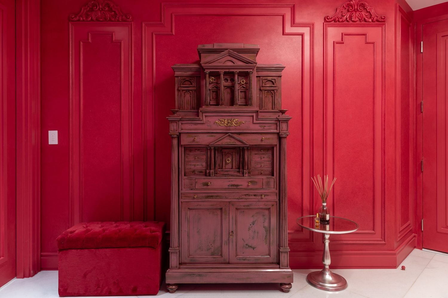 Elevator landing finished in deep red, with antique secretaire and velvet ottoman